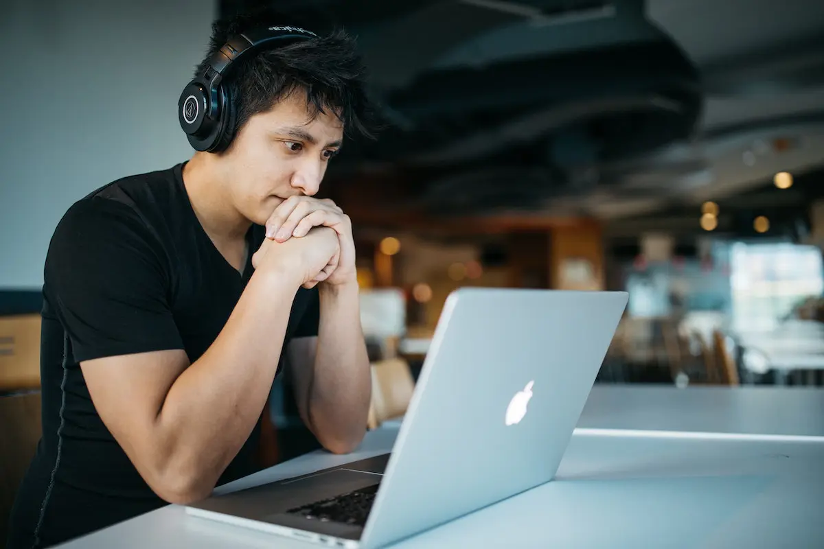 Judging a voice actor's demo: man listening with headphones in front of a laptop