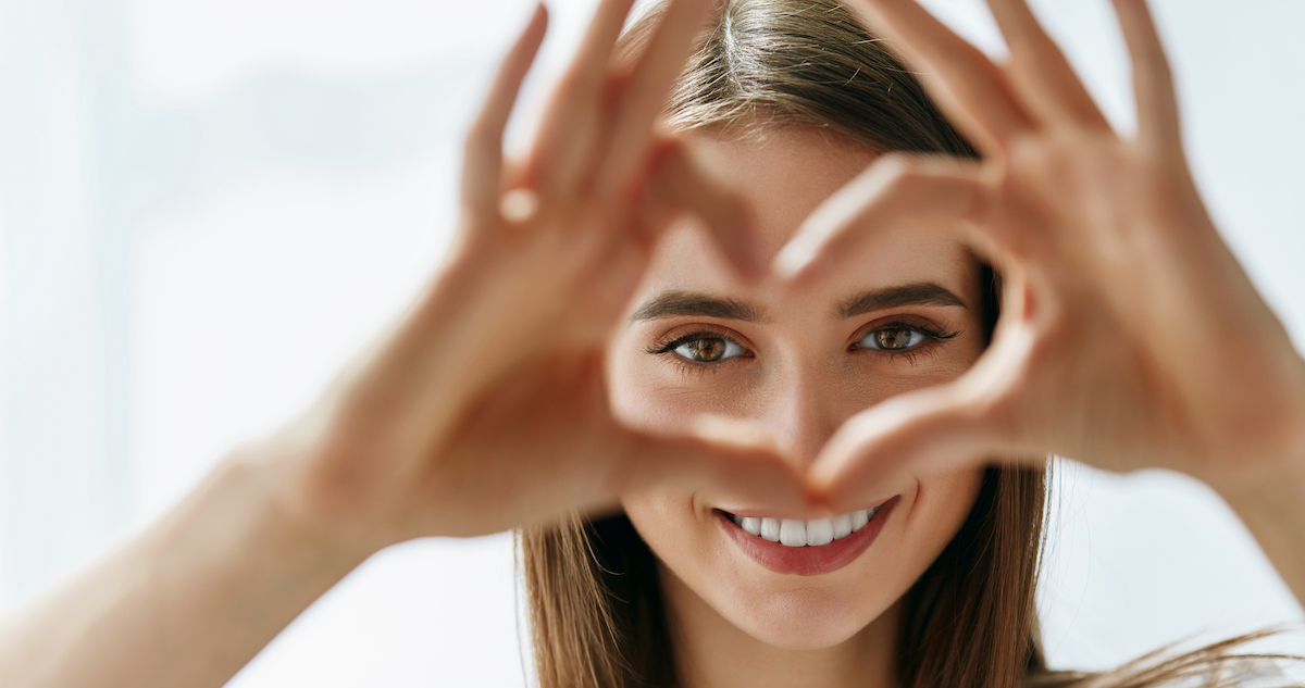 look after your eyes: image of a girl smiling and making a heart-sign with her hands