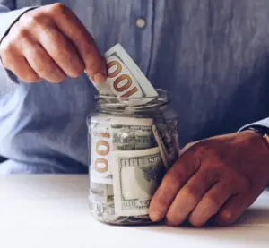 Podcast monetization: image of hands placing paper money into a jar