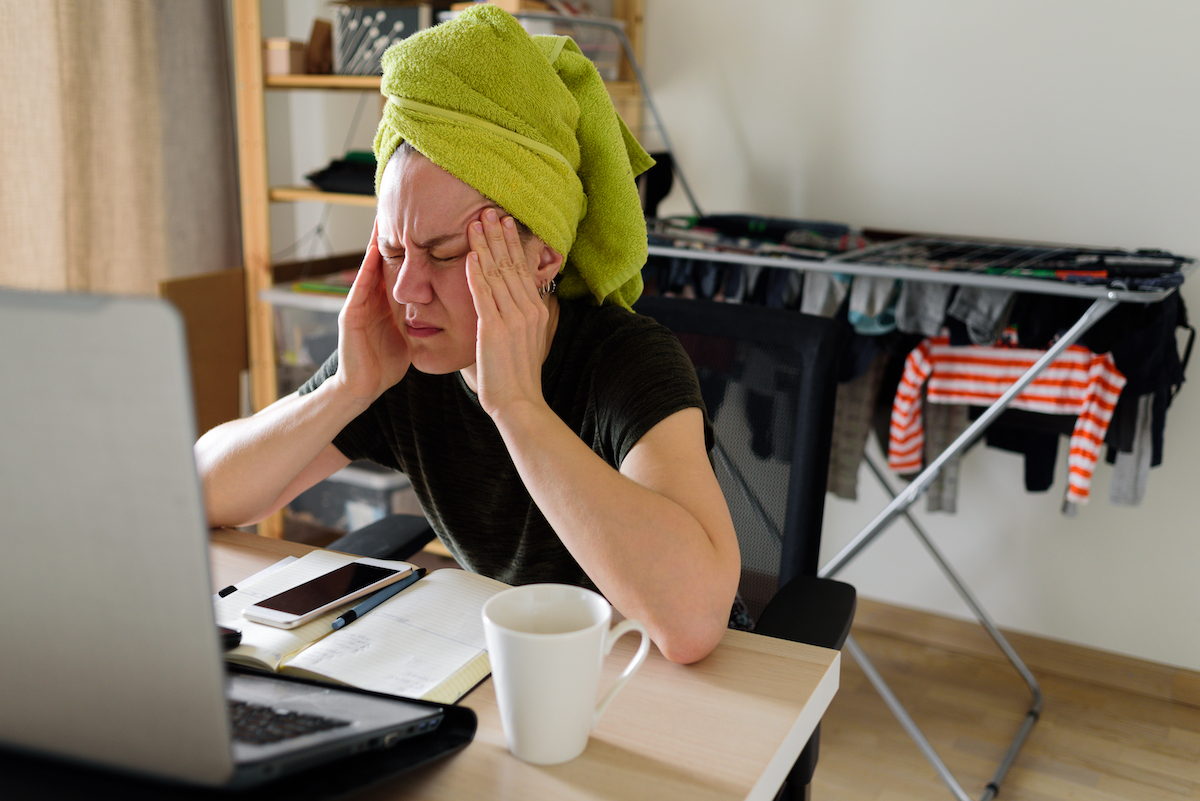 Work from home: image of a woman sitting at her desk with a headache