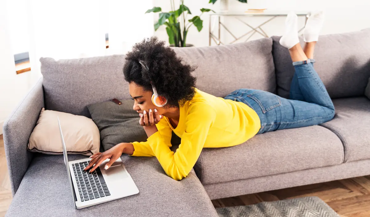 custom auditions:image of a woman with headphones lying on a couch in front of a laptop