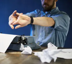 Commercial scriptwriting: image of a man stretching his arms over a typewriter