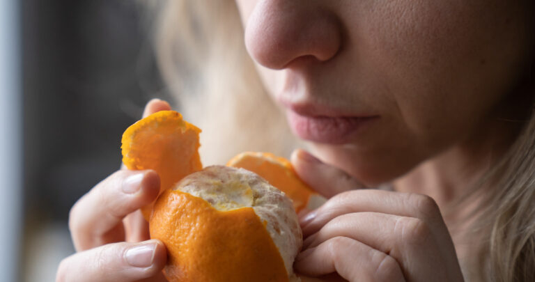 sick-woman-trying-to-sense-smell-of-fresh-tangerin-2021-08-31-01-52-32-utc