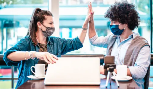 TikTok marketing trends: image of two influencers doing a high-five for the camera