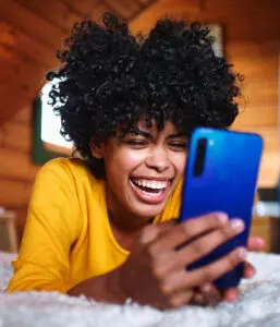 Visual techniques: image of a young woman looking at her phone screen and laughing.