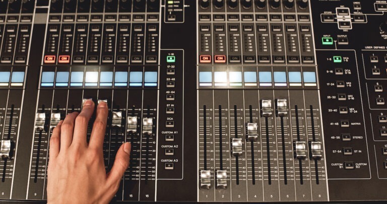 audio gain: image of a hand on an audio mixing desk